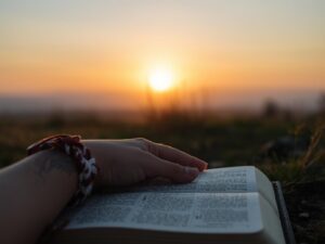 A peaceful dawn landscape with an open Bible and folded hands.)