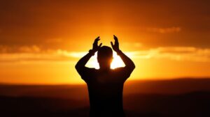 Silhouette praying at sunrise representing renewal and faith.