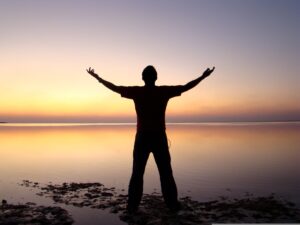 A person stretching at sunrise in prayerful posture