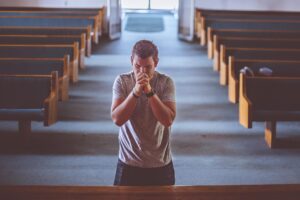 Person kneeling in prayer as dawn breaks through the horizon